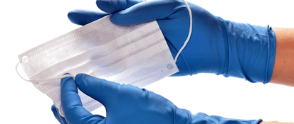 Person wearing blue gloves handling a surgical mask.